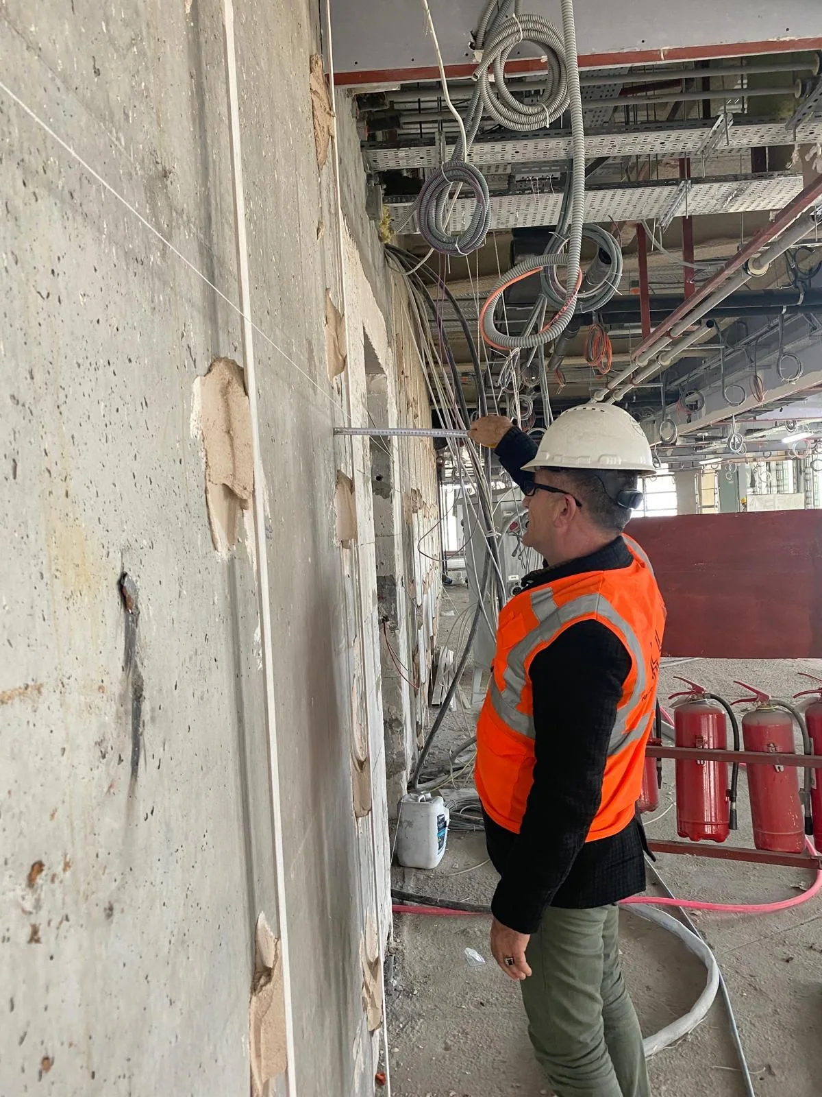 Site team taking measurements along the inner face of the facade