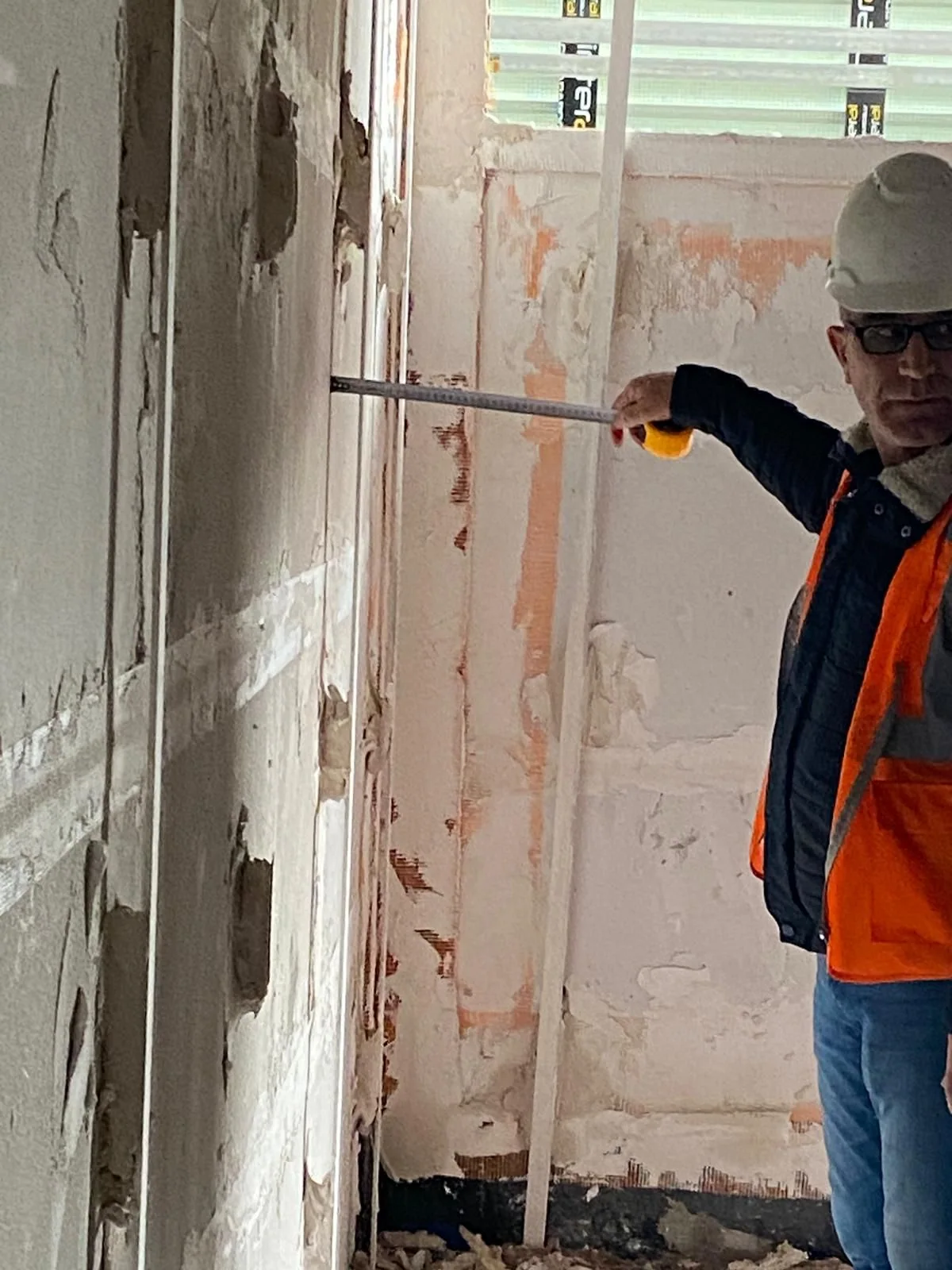 Site team measuring a wall with a tape measure